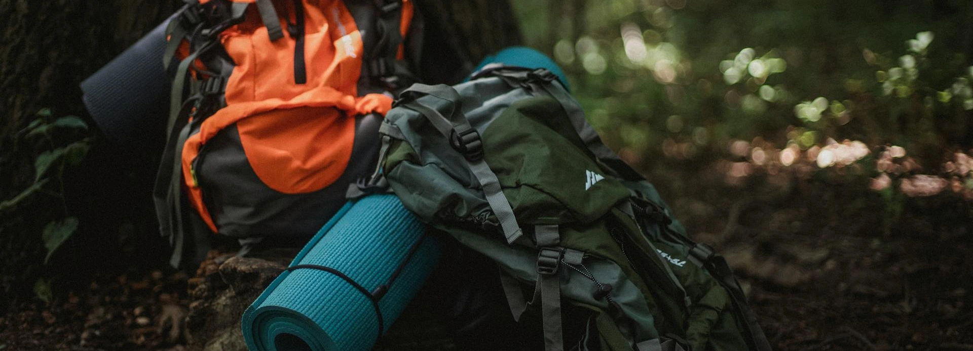 Beginner overnight backpacking gear layout with backpack, tent, sleeping bag, sleeping pad, stove, water filter, food canister, and headlamp.
