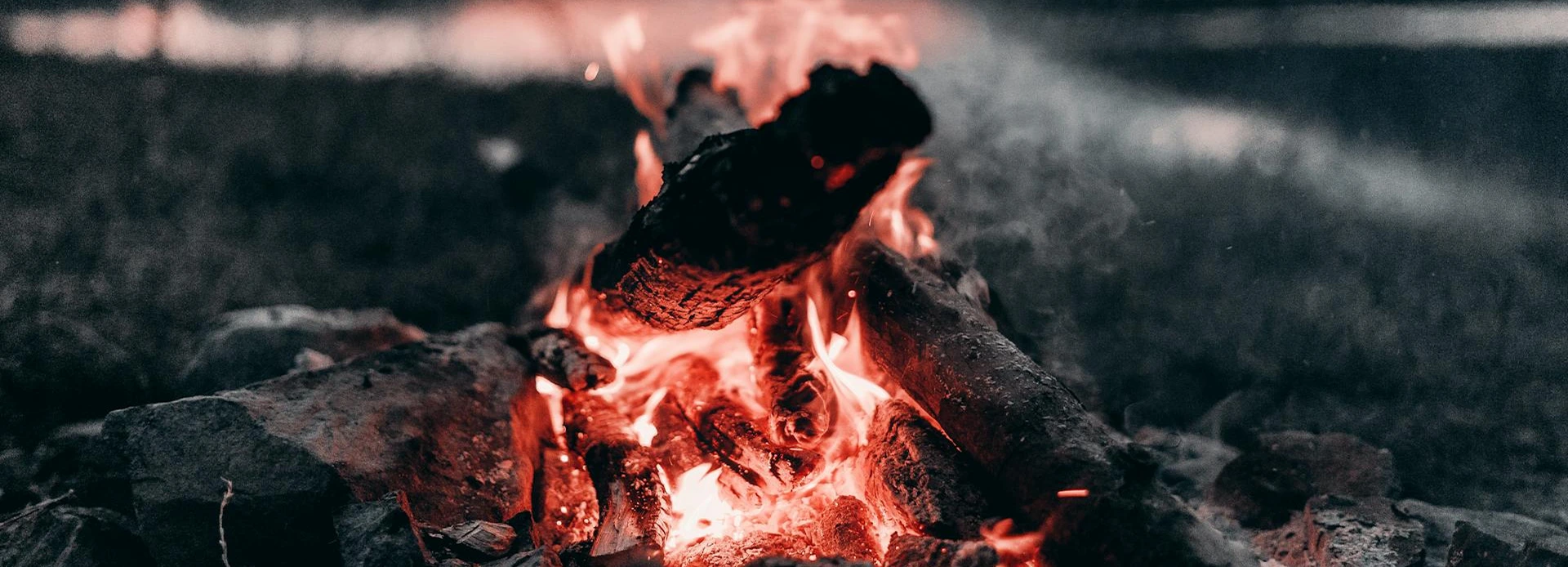 Bushcraft fire starting setup with dry tinder, kindling, ferro rod, prepared wood, and a small controlled campfire.