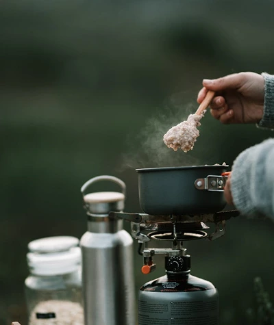 Beginner camp kitchen setup with a camping stove, cookware, cooler, water container, cleanup sink, and food prep area