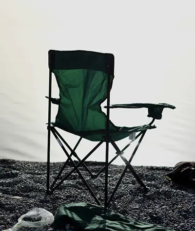 Several camp chairs set up at an outdoor campsite, showing different sizes, frames, and seat heights
