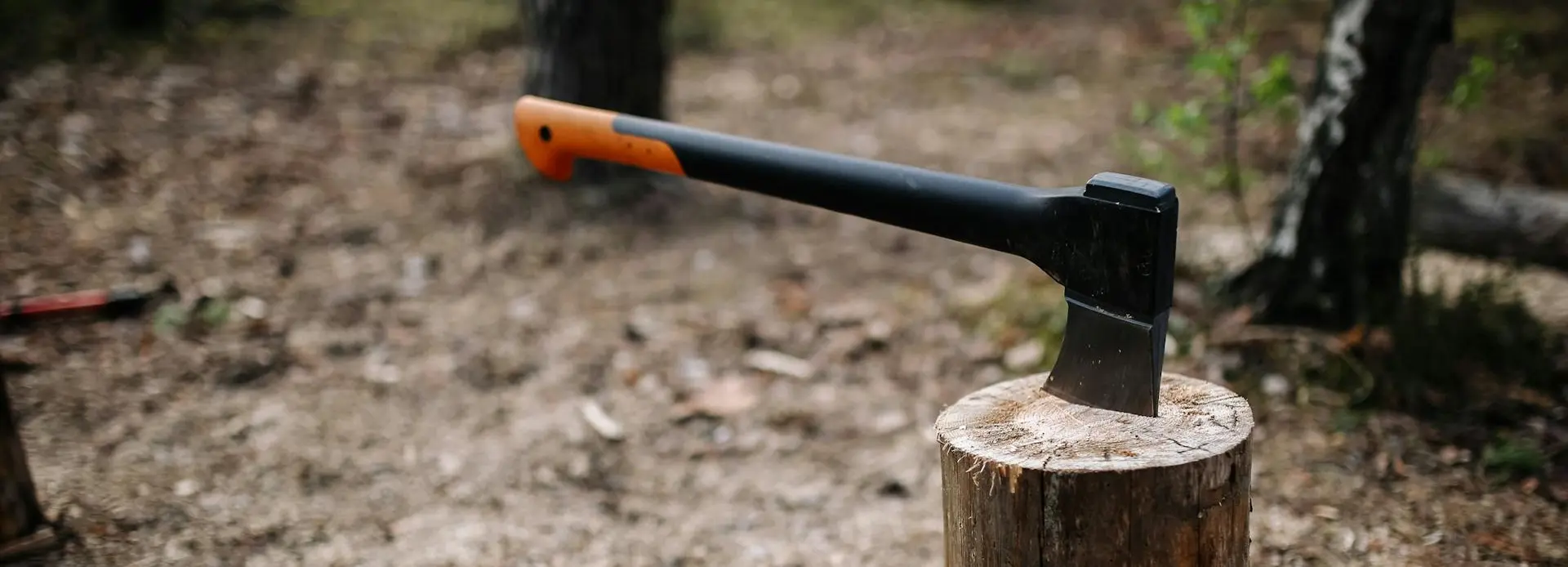 Camp axe with leather sheath, kindling, gloves, and small firewood arranged on a wooden outdoor surface
