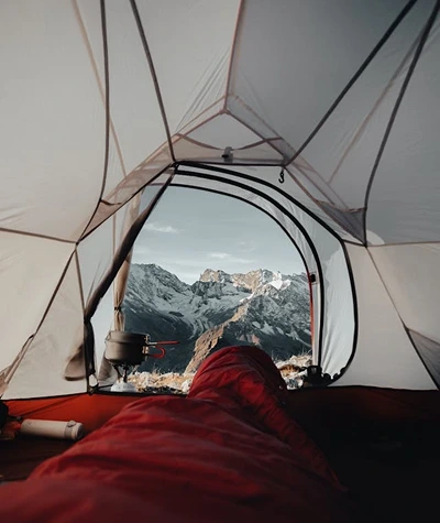 Camping sleep system laid out inside a tent with a sleeping bag, insulated pad, quilt, liner, and dry base layers